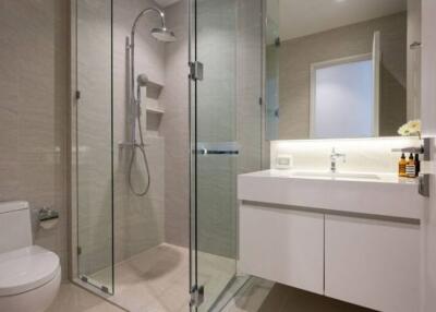 Modern bathroom with glass shower, white vanity, and toilet