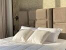 Modern bedroom with beige headboard and white pillows