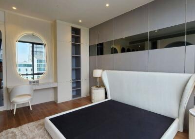 Modern bedroom with large mirror, built-in storage, and two bedside lamps