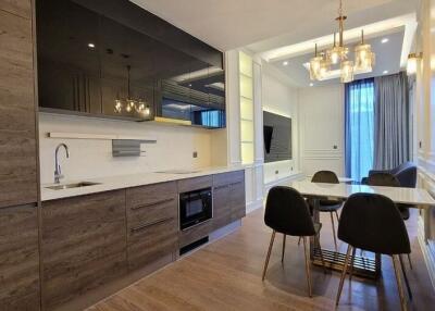Modern kitchen and dining area with wooden cabinetry and elegant lighting
