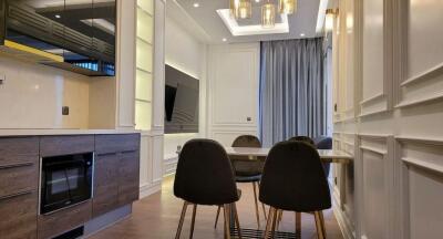 Modern dining area with black chairs, wooden table, and large wall-mounted TV.