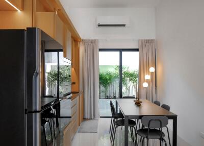 Modern kitchen and dining area with sleek black table, chairs, and built-in appliances