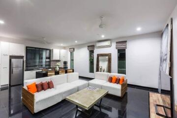 Modern living room with white sofas, coffee table, and open kitchen