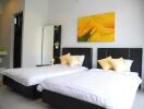A modern bedroom with two single beds and yellow accents