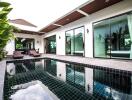 Modern resort-style outdoor pool area with lounge chairs and lush greenery