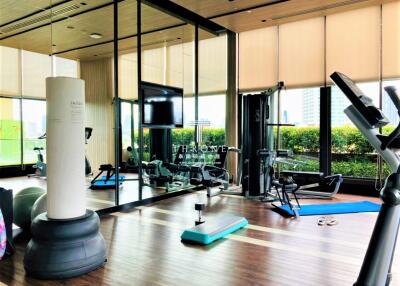 Modern gym with various fitness equipment and a punching bag in a bright, spacious room
