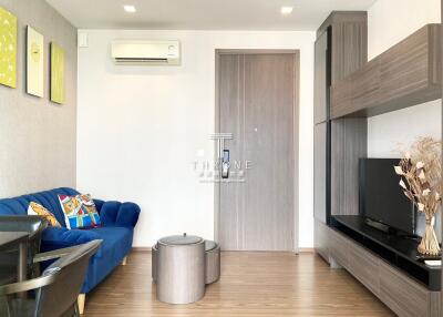 Modern living room with blue sofa, wall-mounted air conditioner, and flat-screen TV