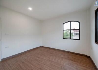 Empty bedroom with wooden floor and arched window