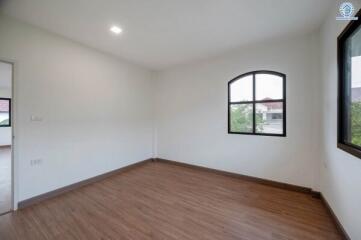 Empty bedroom with wooden floor and arched window