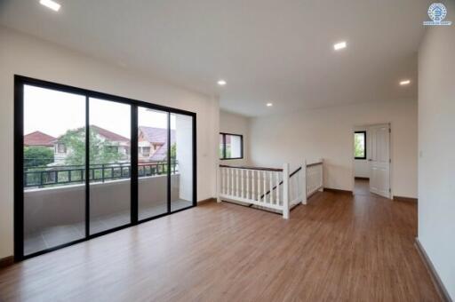 Spacious main living area with large sliding glass doors, balcony access, wooden flooring, and bright natural lighting.
