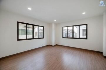 Spacious empty bedroom with wooden floor and large windows