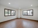 Spacious empty bedroom with wooden floor and large windows