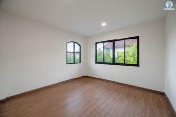 spacious empty bedroom with hardwood floors and large windows