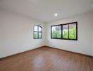 spacious empty bedroom with hardwood floors and large windows