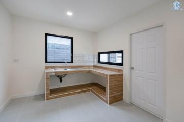 Modern kitchen with light wood cabinets and countertops, including a sink and black-framed windows