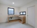 Modern kitchen with light wood cabinets and countertops, including a sink and black-framed windows