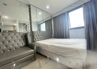 Modern bedroom with large mirror, grey upholstered bed, and matching sofa