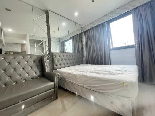 Modern bedroom with large mirror, grey upholstered bed, and matching sofa