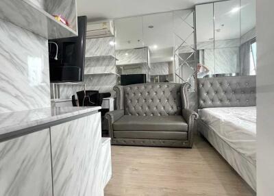 Modern bedroom with marble finishes, a grey sofa, and mirrored walls