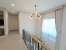 Bright hallway with modern chandelier and large window