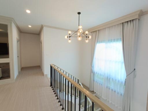 Bright hallway with modern chandelier and large window