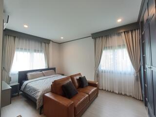 Spacious bedroom with a comfortable bed, sofa, and ample natural light