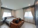 Spacious bedroom with a comfortable bed, sofa, and ample natural light