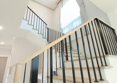 Modern staircase in a well-lit area with black railing and large window