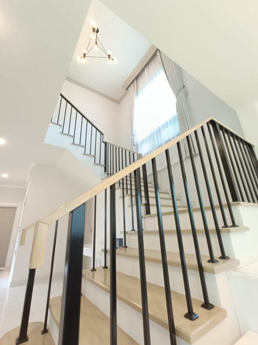 Modern staircase in a well-lit area with black railing and large window