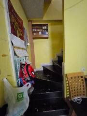 A cluttered staircase area in a home with children’s bags hanging and storage shelves