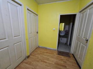 A hallway with yellow walls and three doors.