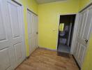 A hallway with yellow walls and three doors.