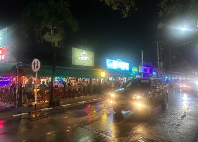 Night view of a bustling street with eateries and neon signs