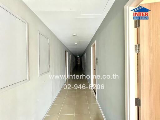 Long hallway in a building with multiple doors and tiled flooring.