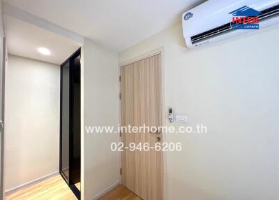 Interior view of a room with a door, air conditioner, and hallway