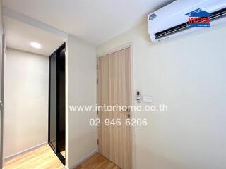 Interior view of a room with a door, air conditioner, and hallway