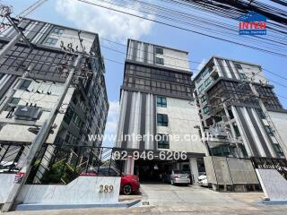 View of a modern apartment building complex with multiple stories and parking area.