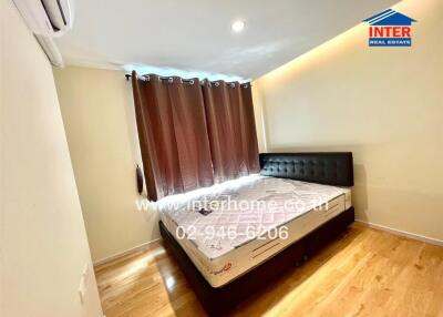 Bedroom with a double bed, brown curtains, wooden floor, and an air conditioner.