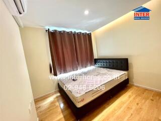 Bedroom with a double bed, brown curtains, wooden floor, and an air conditioner.