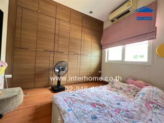 Spacious bedroom with large wooden wardrobe, window, air conditioner, and cozy bed