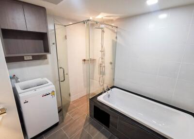 Modern bathroom with bathtub, shower, and washing machine