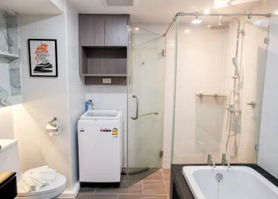 Modern bathroom with bathtub, shower area, and in-unit washing machine