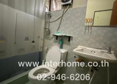 Compact bathroom with toilet, sink, shower, and water heater