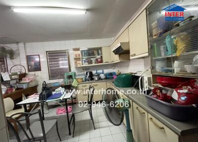 Messy kitchen with cluttered countertops and a dining table with items on it.