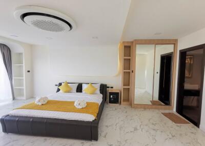 Modern bedroom with large bed, decorative pillows, built-in shelves, and mirrored wardrobe