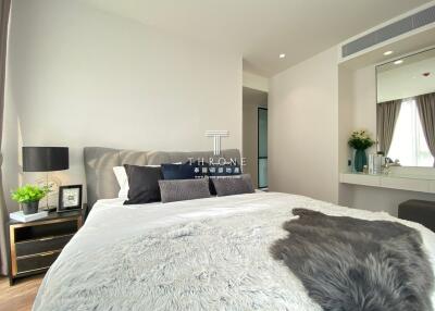 Modern bedroom with a large bed, bedside table, and a vanity area