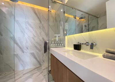Modern bathroom with marble walls and glass shower enclosure