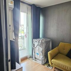 Living room with a small balcony, an air conditioning unit, and a yellow armchair.