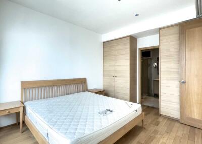 Spacious bedroom with a wooden bed frame, mattress, and built-in wardrobes