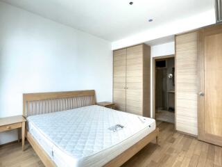 Spacious bedroom with a wooden bed frame, mattress, and built-in wardrobes